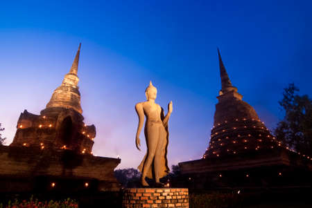 SUKHOTHAI, THAILAND - NOV 20: The statue of a walking Buddha in front of the small and the main stupa at Wat Sa Si on November 20, 2010, Sukhothai, Thailandのeditorial素材