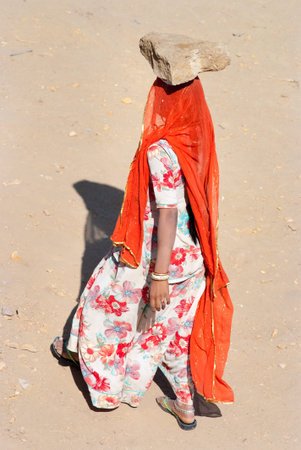 JAISALMER, INDIA - FEB 25  A woman carries a brick on her head on a construction site on Feb 25, 2013 in Jaisalmer, India  Construction is the third-largest employer of women in Indiaのeditorial素材