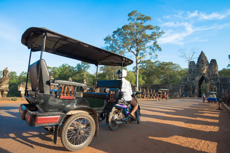 SIEM REAP, CAMBODIA - May 4: Tuk-tuk driver waits for customers at the gate of Angkor Thom on May 4, 2015 in Siem Reap. Tuk-tuks are the most common and popular way to get around Siem Reap.のeditorial素材