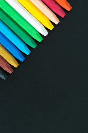 Row of multi colored wax crayons on the black board