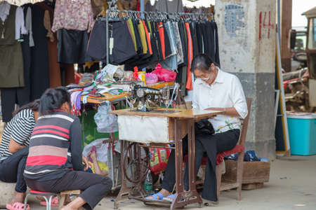 GUILIN, CHINA â SEPTEMBER 18, 2017: customers wait for their cloths to be mended at a local morning market in Guilinのeditorial素材