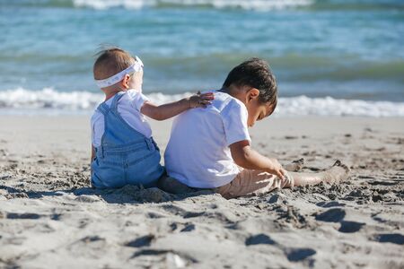Sister and brother sit on the beach and look at the sea. の写真素材