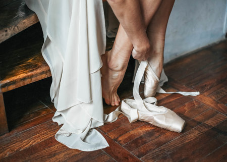 Close up for ballet dancer putting on, tying ballet shoes. Ballerina putting on her pointe shoes.
