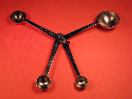 4 measuring spoons, connected but spread out, of various sizes. Shot against a red backlit background.の写真素材