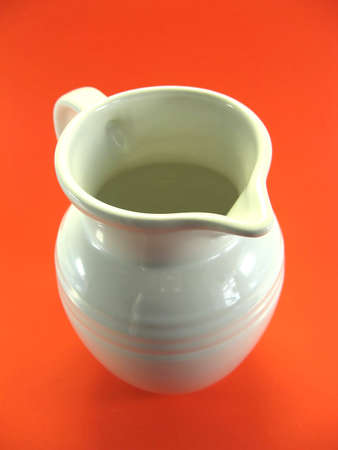 Plain white milk jug on orange backgroundの写真素材