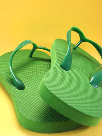 green plastic flip flops against colored backgroundの写真素材