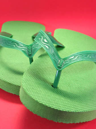 green plastic flip flops against colored backgroundの写真素材