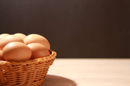 The eggs in the brown wicker basket on the table. Close-up view.の写真素材