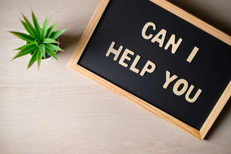 Wooden letters CAN I HELP YOU on the blackboard. Top view.の写真素材