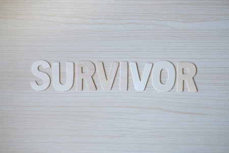 The word SURVIVOR, Wooden letters on a wooden table. Top view.の写真素材