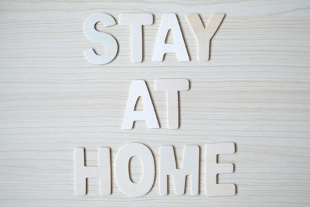 The word STAY AT HOME, Wooden letters on wooden table. Top view.の写真素材