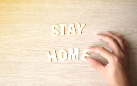 The word STAY HOME, The placement of wooden letters on wooden table. Top view.の写真素材