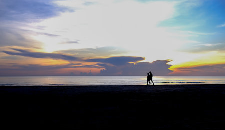 silhouette of a couple walking on the beach in the morningの写真素材