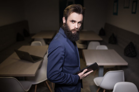 bearded man in suit and with tablet in cafe;の写真素材