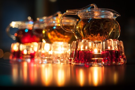 three glass teapots with candle heaters; cute transparent teakettles with fire heat;の写真素材