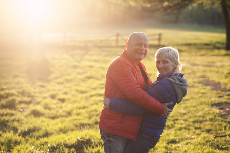happy seniors couple embrace and smile; older male and female in park;の写真素材