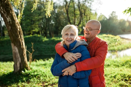 happy seniors couple embrace and smile; older male and female in park;の写真素材