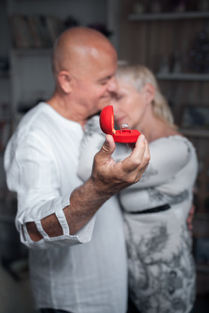 senior man making proposal to older woman; older male hug female and with wedding ring in hand;の写真素材