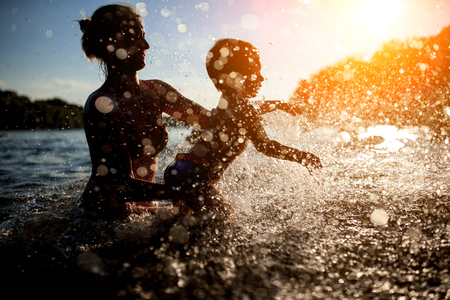 female with child bathe in lake or river and making water drops;の写真素材