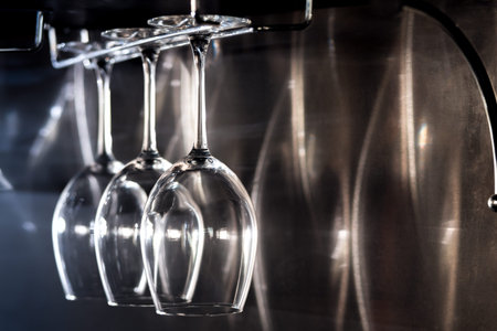 three wine glasses hanging on bar rack; wineglasses equipment for restaurant or cafe;