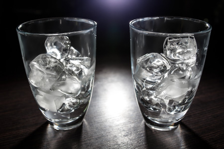 two empty glasses with ice cubes; few transparent cups with cold icecubes;の写真素材