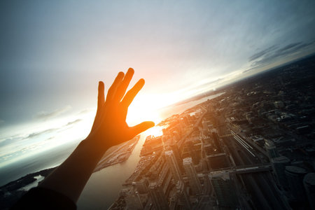 hand closing from sun light on roof top of city;の写真素材