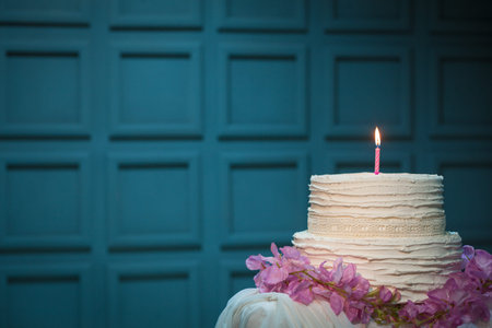 birthday cake with burning candle on blue background; homemade delicious sweet dessert with flowers...