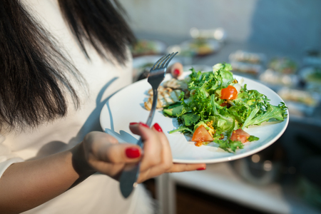 female holding healthy organic food; woman keeps plate with salad;の写真素材