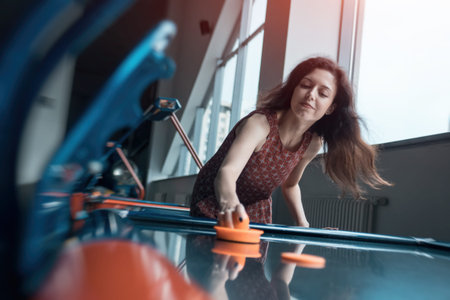 beautiful brunette female playing air hockey with friend