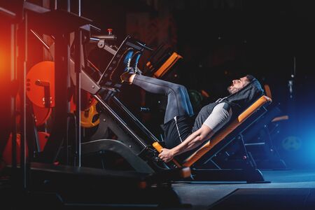 young man has legs workout in modern gymの写真素材