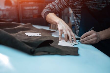 man shaping leather for shoe with knife on factoryの写真素材