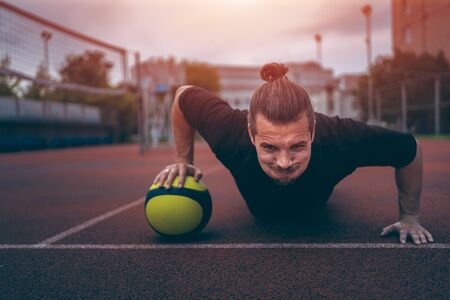 muscular young athlete has workout and exercising with medicine ball outdoorの写真素材