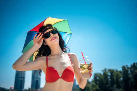 beautiful female rest on city beach with umbrella and drink mojito cocktail