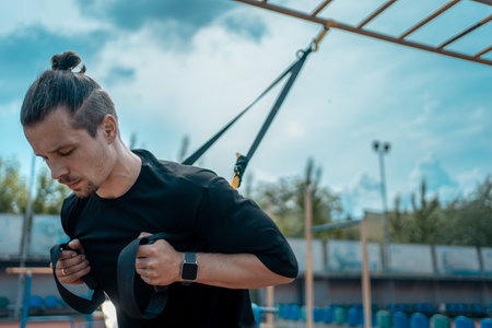 yound sporty athlete or bodybuilder has fitness workout with trx outdoor