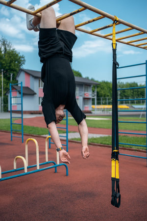 yound sporty athlete or bodybuilder has fitness workout with trx outdoor