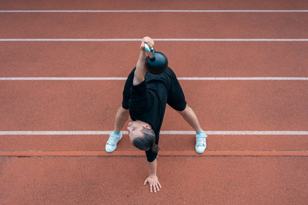 young athlete has workout and doing sport exercises with kettlebell outdoor