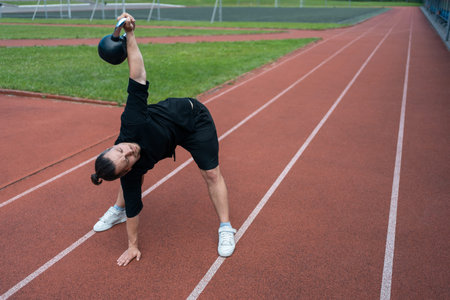 young athlete has workout and doing sport exercises with kettlebell outdoor