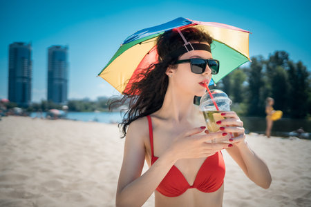 beautiful female rest on city beach with umbrella and drink mojito cocktail