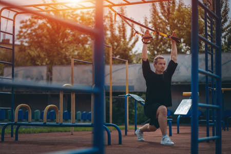 young sporty athlete or bodybuilder has fitness workout with trx outdoorの写真素材