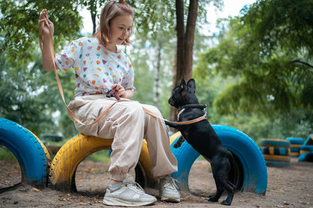 girl play with cute little frenchie bulldog puppy in park at summer dayの写真素材