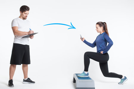 young female workout with personal fitness trainer on smartphone online isolatedの写真素材