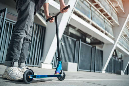 young teenager in sneaker on modern extreme stunt kick scooter in skateparkの写真素材
