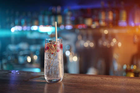 modern gin tonic cocktail with ice, straw and red berries on bar counterの写真素材
