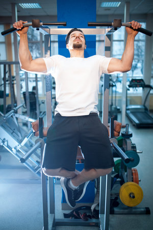 young athletic male has personal workout and pull up on bar in gym
