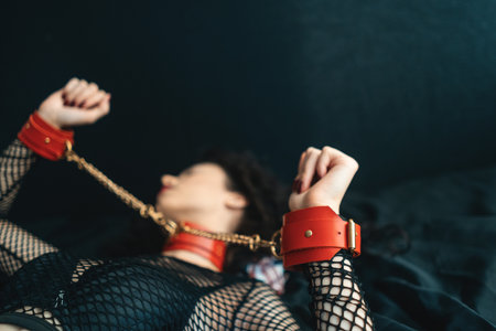 Sensual female with red lips, leather bondage collar choker and handcuffの写真素材