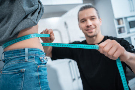 fitness nutritionist man measure woman waist with measuring centimeter tape