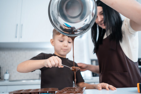 happy mother and kid making chocolate candies or sweets at home modern kitchenの写真素材