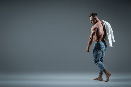 young handsome man bodybuilder posing with perfect torso on grey backgroundの写真素材