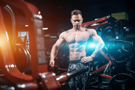 young athletic sportsman bodybuilder with muscle perfect body posing in gym