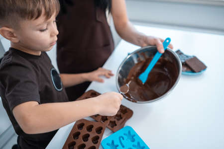 happy mother and kid making chocolate candies or sweets at home modern kitchenの写真素材